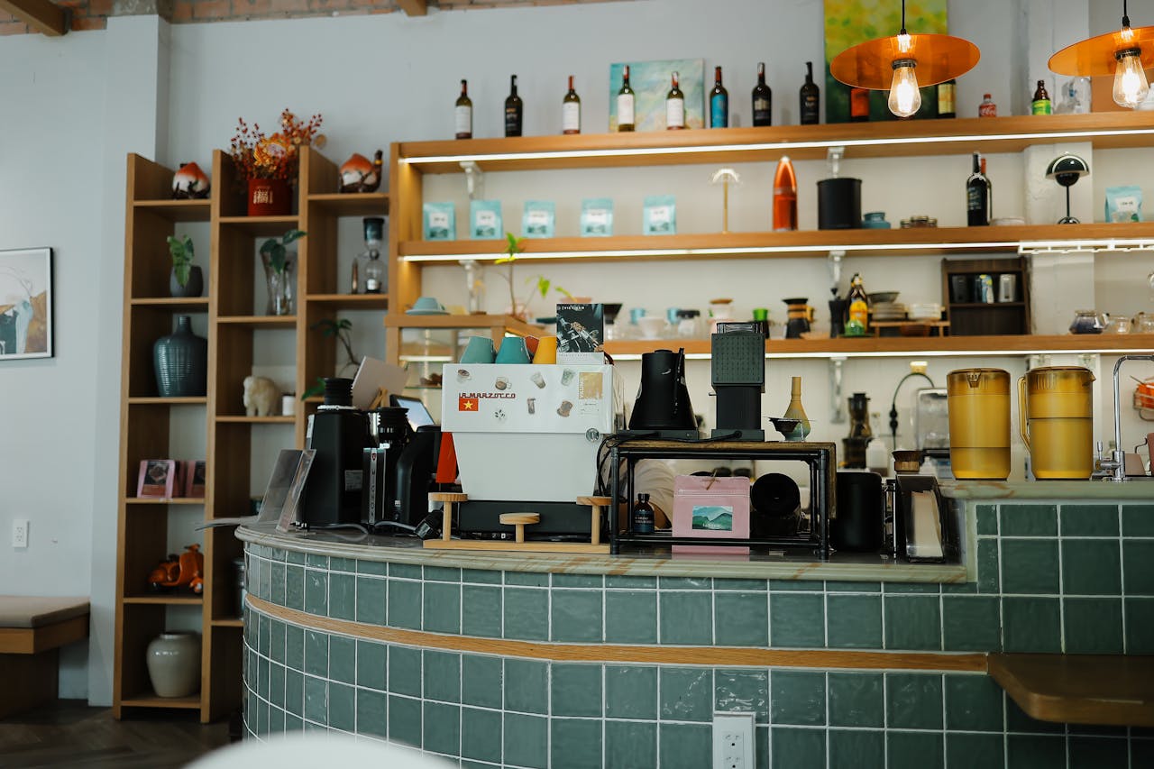 Cozy coffee shop interior featuring a green tile counter, espresso machine, and stylish decor.